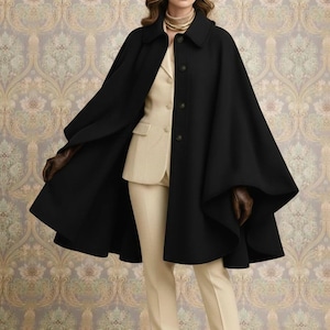 Op de afbeelding: Een vrouw draagt een zwarte capejas met een beige pak, een bruine hoed en bruine handschoenen. De jas heeft een knoopsluiting en een wijd, vloeiend ontwerp. De outfit wordt gecompleteerd met een beige broek en bruine laarzen. De achtergrond heeft een bloemenpatroon.