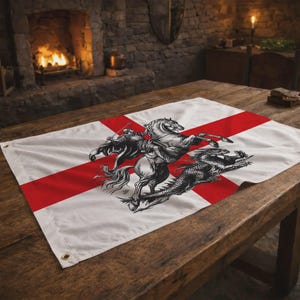 Puede incluir: Bandera blanca con una cruz roja y una ilustración detallada de un caballero a caballo matando a un dragón. La bandera es de tela y tiene ojales para colgarla. Se muestra sobre una mesa de madera.