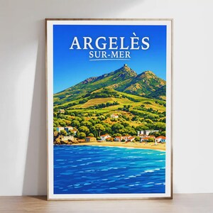 Könnte beinhalten: A framed poster with the text "ARGELÈS SUR-MER" above a coastal landscape. The image shows a beach, blue sea, green hills, and white buildings under a bright blue sky, evoking a sense of travel.