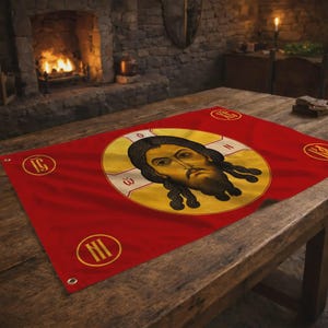 Op de afbeelding: Rode banner met een religieuze icoon, gouden halo en gedetailleerd gezicht. Gouden cirkelvormige accenten met tekst en ogen zijn zichtbaar. De banner wordt op een houten tafel gepresenteerd.