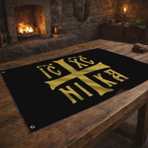 May include: Black banner with a gold cross design and the Greek words "IC XC NIKA". The banner is displayed on a wooden table. The background includes a fireplace and a stone wall.