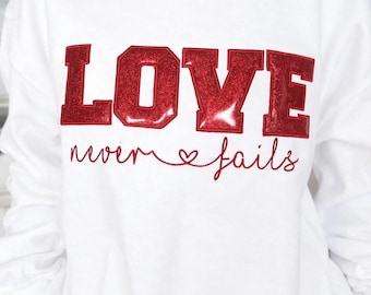 Sudadera bordada "El amor nunca falla", prenda inspiradora sobre la fe.
