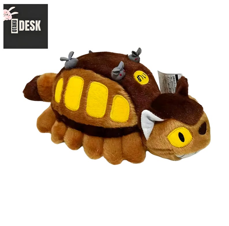 Puede incluir: Un peluche con forma de oruga marr&oacute;n y beige con detalles amarillos. El juguete tiene una cara sonriente y peque&ntilde;os detalles grises en la espalda. El texto "OTAKU DESK" est&aacute; en la esquina superior izquierda.