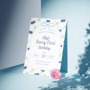 May include: A birthday invitation featuring a blue and white gingham design, decorated with blueberries and yellow flowers. The text says "Ally's Berry First Birthday" with the date and time. A pink flower is at the bottom.