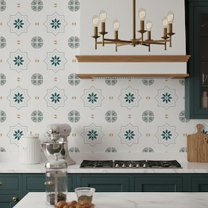 以下が含まれることがあります： 白いカウンタートップ、濃い緑色のキャビネット、模様入りのバック スプラッシュを備えたキッチン。 バック スプラッシュは、ターコイズの花と幾何学模様の繰り返しデザインが特徴です。 真鍮のシャンデリアがコンロの上に吊り下げられています。