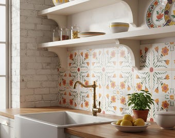 May include: A kitchen scene featuring a white farmhouse sink, a brass faucet, and wooden countertops. White shelves hold bowls, plates, and jars. The backsplash is tiled with a floral pattern in orange, green, and white. A small potted plant and a bowl of lemons add color.