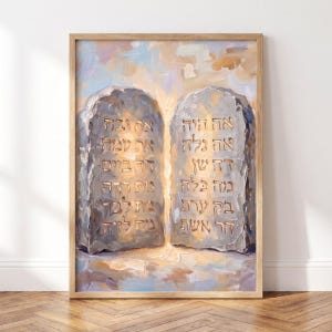 Könnte beinhalten: Ein gerahmtes Ölgemälde, das zwei Steintafeln mit hebräischem Text in goldener Schrift zeigt. Die Tafeln sind in Grau-, Blau- und Cremetönen mit sichtbaren Pinselstrichen gemalt und vor einem hellen, abstrakten Hintergrund platziert.