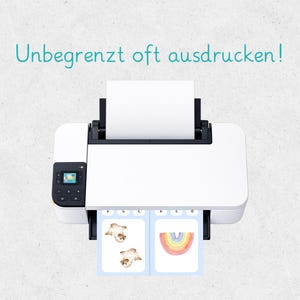 May include: A white printer with a black control panel is printing two cards. One card has two illustrations of a seal, and the other has a watercolor rainbow. The text "Unbegrenzt oft ausdrucken!" is above the printer.