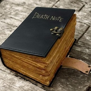 Peut inclure: Un journal en cuir noir avec les mots "DEATH NOTE" estampés sur la couverture. Les pages sont vieillies, et le journal est sécurisé par un fermoir en métal et une lanière en cuir.