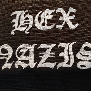 May include: Black fabric patch with white embroidered text that reads "HEX RAIS".