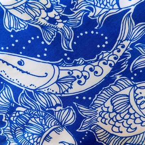 Peut inclure: Gros plan sur un tissu bleu et blanc avec un motif de poissons r&eacute;p&eacute;t&eacute;. Les poissons sont stylis&eacute;s avec des contours d&eacute;taill&eacute;s et des &eacute;l&eacute;ments d&eacute;coratifs. Le fond est bleu uni, et le design &eacute;voque un th&egrave;me nautique.