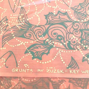 Peut inclure: Tissu corail avec un motif de poissons et de fleurs turquoise, agr&eacute;ment&eacute; de points blancs. Le texte "GRUNTS BY ZUZEK - KEY WE" est imprim&eacute; en bas. Le motif pr&eacute;sente des poissons stylis&eacute;s et des lignes tourbillonnantes.