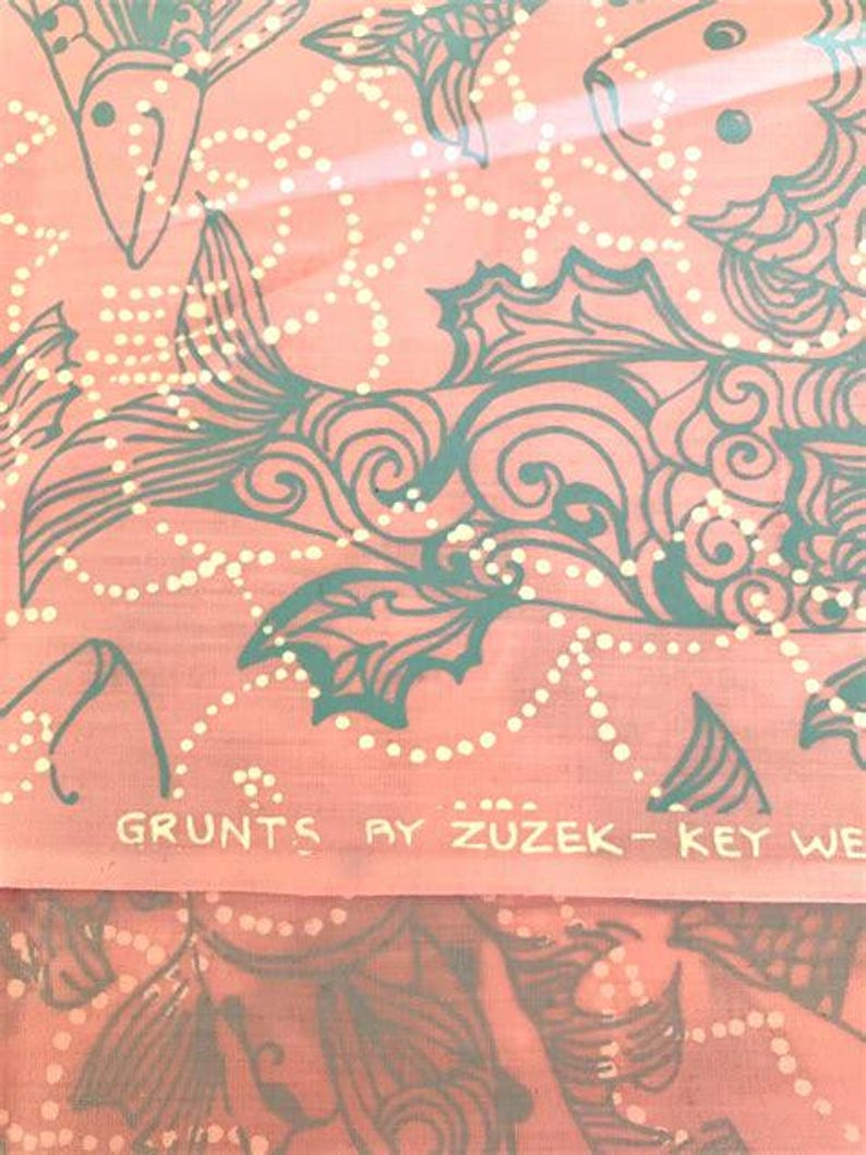 Peut inclure: Tissu corail avec un motif de poissons et de fleurs turquoise, agr&eacute;ment&eacute; de points blancs. Le texte "GRUNTS BY ZUZEK - KEY WE" est imprim&eacute; en bas. Le motif pr&eacute;sente des poissons stylis&eacute;s et des lignes tourbillonnantes.