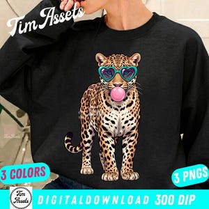Puede incluir: Sudadera negra con una ilustración de leopardo con gafas de sol en forma de corazón y soplando una burbuja de chicle. El leopardo tiene un patrón de manchas. La imagen incluye el texto "3 COLORES" y "3 PNGS".