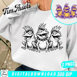 May include: White sweatshirt featuring a black and white graphic of three cartoon frogs with spiky hair and open mouths. The design includes a circular image of the same frogs in yellow and purple. The text "Tim Assets" is visible.