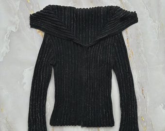 May include: A black long-sleeve sweater featuring a wide, folded-over off-the-shoulder collar and a vertical ribbed knit texture. The fabric is woven with subtle silver metallic threads throughout, and the garment includes a full-length front zipper.