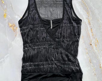 May include: A sleeveless black top featuring a pleated, shimmering silver texture across the bodice. The garment has a deep V-neckline accented with a vertical row of small clear rhinestones and a solid black hem band at the bottom edge.