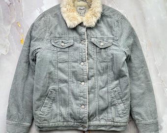 May include: A light gray corduroy jacket with a cream-colored faux fur collar. The jacket has two chest pockets, two side pockets, and a button-up front. The lining is a cream-colored faux fur.