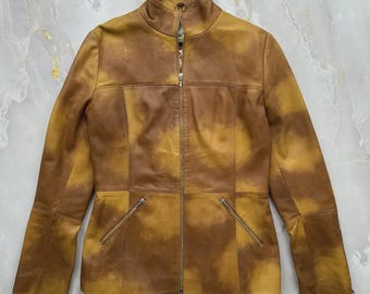 May include: A brown leather jacket with a high collar and a full-length zipper. The jacket has two zippered pockets on the front and a tailored fit. The leather has a mottled, two-tone appearance.