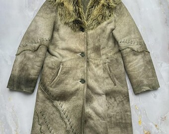 May include: A long, olive-green coat with a textured, weathered finish and a thick, matching faux fur collar. The coat features three front buttons, long sleeves, and decorative whip-stitch detailing along the sleeves and the front panel.