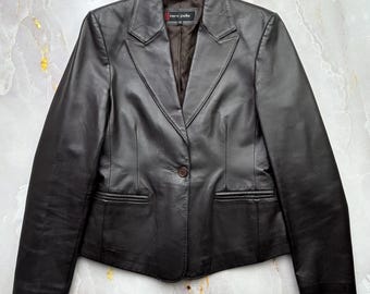 May include: A dark brown leather blazer with a single-button closure and two front pockets. The blazer has a classic lapel design and a tailored fit. The label reads "vero pelle".