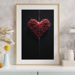 Könnte beinhalten: Gerahmtes Kunstwerk mit einem roten Herzdesign auf schwarzem Hintergrund. Das Herz besteht aus rotem Faden und erzeugt einen strukturierten, dreidimensionalen Effekt. Das Kunstwerk ist in einem goldenen Rahmen.