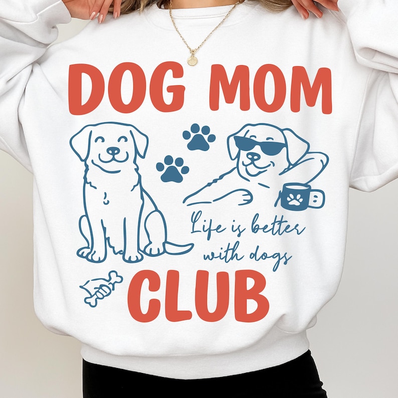 Model wearing a Dog Mom Club sweatshirt featuring cute dog illustrations, paw prints, and “Life is better with dogs” quote. Great for cozy outfits, pet lovers, and dog mom gifts.