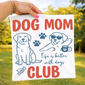 Dog Mom shirt mockup held outdoors featuring playful dog graphics, paw prints, and bold “Dog Mom Club” text. Perfect for dog owners, pet moms, and animal lovers. Great for Cricut, sublimation, and custom apparel.