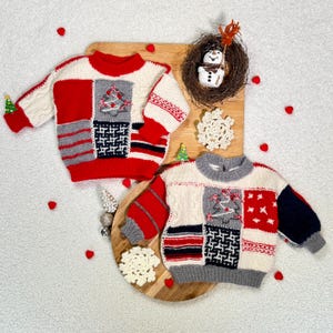 Könnte beinhalten: Zwei Weihnachtspullover mit rot-weiß-grauen Patchwork-Designs. Jeder Pullover hat eine Weihnachtsbaum-Applikation und einen rot-weiß gestreiften Ärmel. Eine Schneemann-Dekoration und Schneeflocken-Ornamente sind ebenfalls vorhanden.