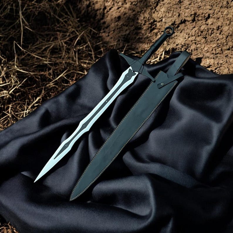 May include: A black and silver sword with a matching black sheath rests on a black satin cloth. The sword has a long, double-edged blade with a decorative design. The sheath is made of black leather.