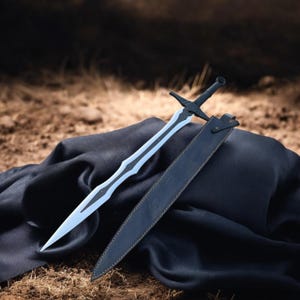 May include: A black sword with a silver blade and a matching black sheath. The sword is lying on a black cloth, with a brown background. The sword has a unique design.