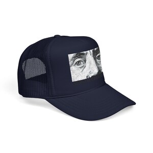 May include: Navy blue trucker hat featuring a black and white graphic of a close-up of eyes. The hat has a mesh back and a curved brim. The graphic is a detailed illustration.