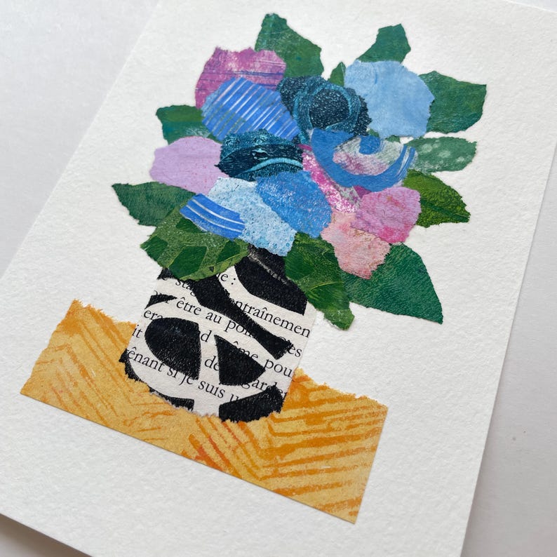 May include: A collage of paper flowers in shades of blue, pink, and green, arranged in a black and white striped vase. The vase is sitting on a yellow and orange patterned surface. The text "entra&icirc;nemen &ecirc;tre au po" is visible on the vase.