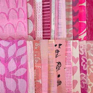 May include: A collage of vertical paper strips in various shades of pink, featuring printed French text, hand-painted leaf patterns, circular motifs, striped textures, black bird illustrations, and heart shapes arranged in a dense, layered composition.