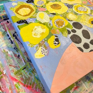 May include: Abstract floral artwork featuring bright yellow flowers with textured centers and green leaves against a light blue background. The vase is a light peach color with a black and white polka dot pattern. The artwork is signed with the initials "cp".