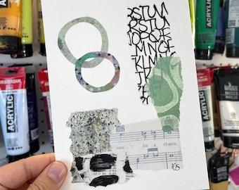 May include: A white card with a collage of paper scraps. The collage includes a green and white abstract design, a black and white musical score with the words "wait for a chance", and a black and white alphabet. The card is surrounded by tubes of acrylic paint.