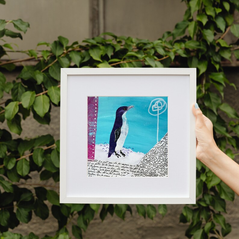 Puede incluir: Una obra de arte enmarcada que presenta un ping&uuml;ino blanco y negro de pie sobre un fondo blanco y azul. La obra de arte incluye una nota escrita a mano con texto sobre el ping&uuml;ino.