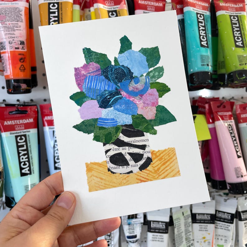 May include: A collage art piece featuring a bouquet of flowers in a black and white striped vase. The flowers are made of paper and are in shades of blue, pink, and green. The vase is sitting on a yellow and orange background with text from a book.