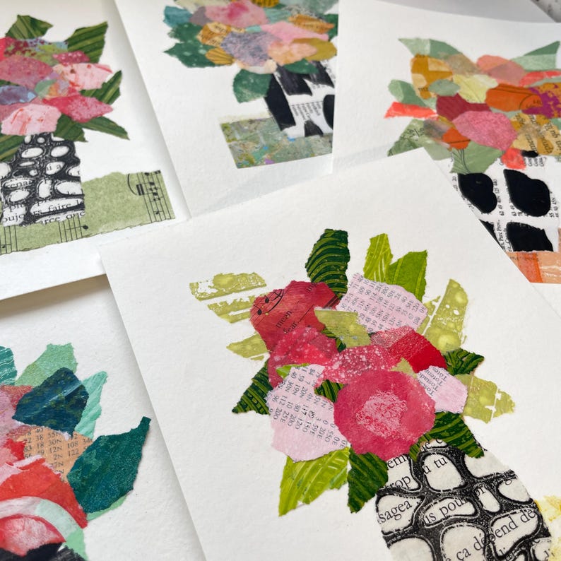 May include: A collage of paper flowers in a vase. The flowers are pink, red, and white, and the vase is made of paper and has a black and white pattern. The background is white.
