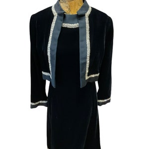 May include: A black velvet dress with a matching jacket. Both pieces feature silver trim with a beaded design.