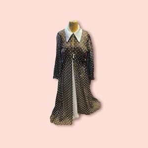 May include: A black and white polka dot dress with a white collar and long sleeves. The dress is made of a sheer fabric and has a flowing silhouette.