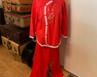 May include: Red pajama set with white trim and floral embroidery on the top. The top has a mandarin collar and a button closure.