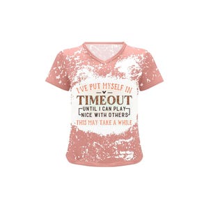 May include: A pink V-neck t-shirt with a distressed white design. The shirt features the text "I'VE PUT MYSELF IN TIMEOUT UNTIL I CAN PLAY NICE WITH OTHERS THIS MAY TAKE A WHILE" in a mix of fonts.