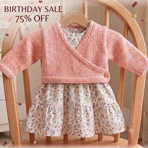 May include: A long-sleeved peach-colored knit wrap cardigan with a single wooden button closure layered over a white dress featuring a delicate floral pattern with small blue, pink, and green flowers. The text BIRTHDAY SALE 75% OFF is visible.
