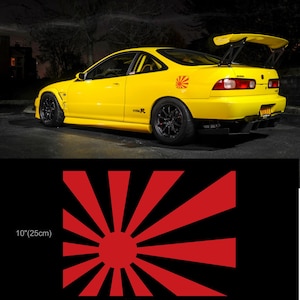 May include: A bright yellow sports car with black wheels and a rear spoiler. A red and white rising sun decal is on the rear quarter panel. The decal is 10 inches (25 cm) by 8 inches (20 cm).