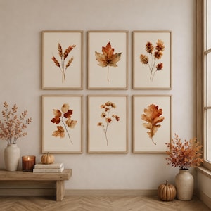 Peut inclure: Un ensemble de six cadres muraux présentant des illustrations à l'aquarelle de feuillage d'automne, incluant du blé, des feuilles d'érable et de chêne dans des tons orange et marron, disposés dans des cadres en bois clair sur un mur neutre.