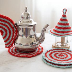Peut inclure: Une théière argentée avec un ensemble de dessous de plat, de dessous de verre et de chauffe-tasse en crochet rouge et bleu clair. Les articles faits à la main présentent un motif rayé.