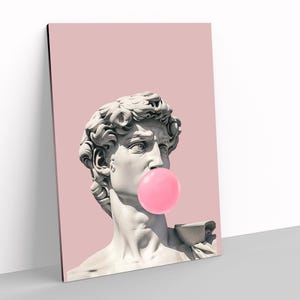 Puede incluir: Una impresión de arte pop que presenta una escultura clásica de un busto con una burbuja de chicle rosa. La escultura está colocada sobre un fondo rosa liso. La obra de arte es una versión moderna del arte clásico.