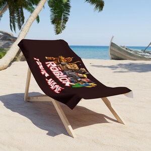 Peut inclure: Chaise de plage marron avec une assise en tissu marron foncé avec le logo et les personnages de Roblox. La chaise est en bois clair et est posée sur une plage de sable avec un bateau et l'océan en arrière-plan.