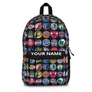May include: Black backpack covered in colorful NBA team logos. The backpack has a front pocket with the text "YOUR NAME" in white. The backpack has a black handle and zipper.